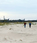 two people walking on sandy beach