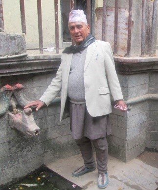 A citizen scientist (Mr. Tek Raj Ghimire, father of Santosh R. Ghimire) points towards a traditional stone-spouts (hiti) in Nepal. (Photo courtesy of Mr. Tek Raj Ghimire).