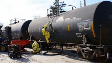 railcar tanks with workers climbing up ladder on tank