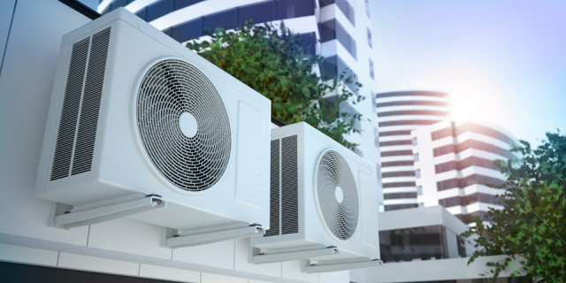 Two air conditioning units with building in the background.