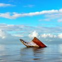 Hull of sunken vessel sticks up above the water line