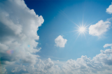 Sun shines in a blue sky with clouds